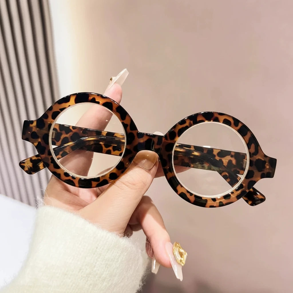 Hand holding round brown leopard-pattern reading glasses