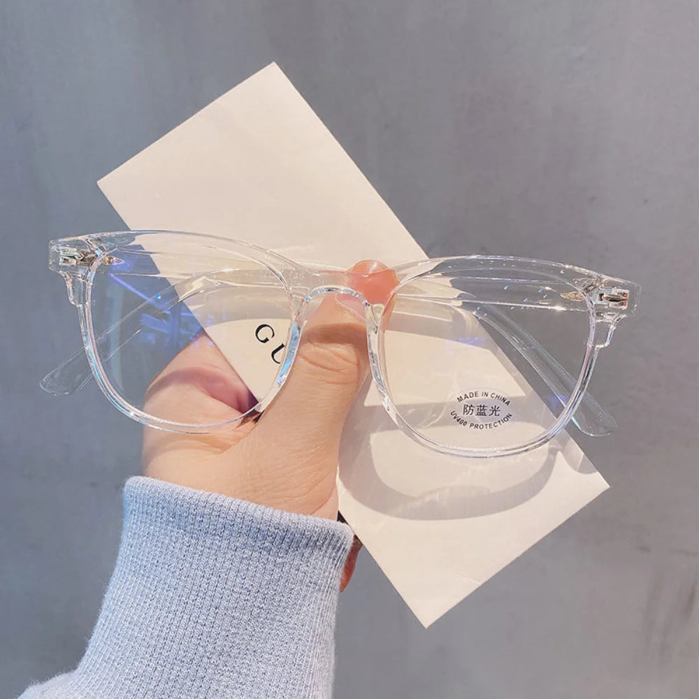 Clear transparent eyeglasses held before a neutral background