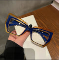 Hand with black nails holding blue orange cat eye glasses