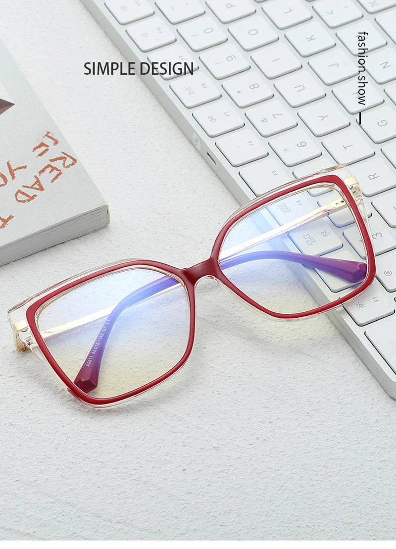 Red-framed blue light protection glasses on white desk near keyboard