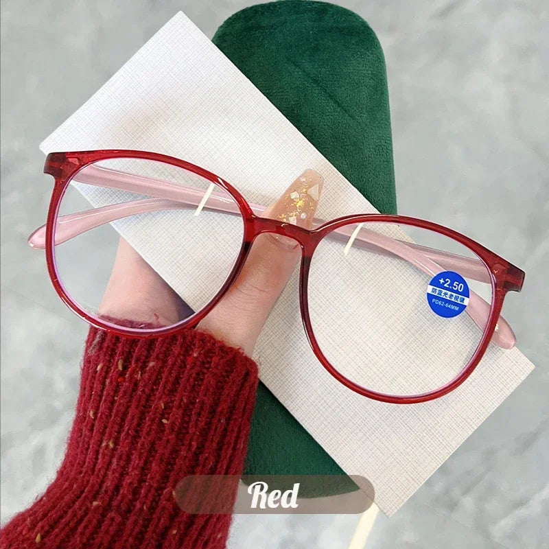 Red round frame reading glasses displayed on a white card